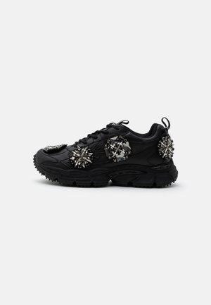Μαύρο chunky sneaker με χοντρή σόλα, διακοσμημένο με τρία μεγάλα ασημένια και μαύρα κοσμημένα σχέδια στο πλάι και στη φτέρνα.