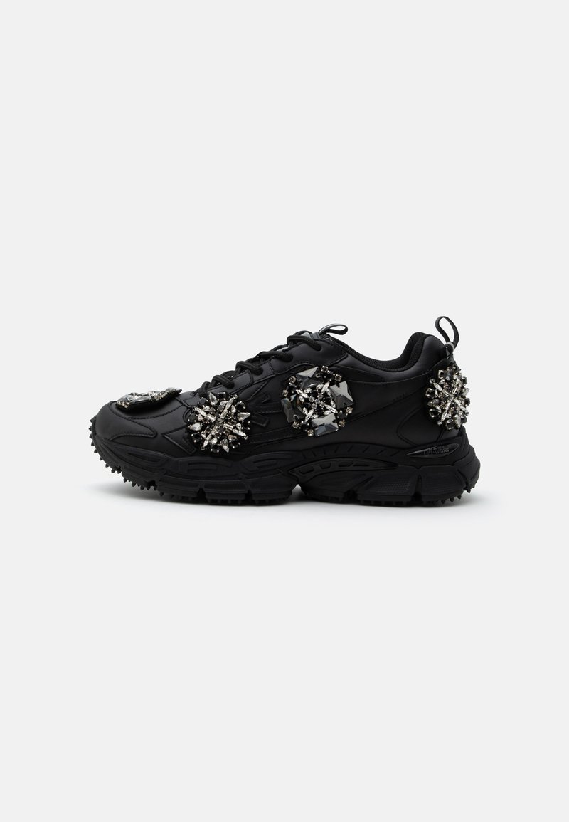 Μαύρο chunky sneaker με χοντρή σόλα, διακοσμημένο με τρία μεγάλα ασημένια και μαύρα κοσμημένα σχέδια στο πλάι και στη φτέρνα.
