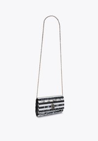 Borsa a tracolla a strisce bianche e nere con una tracolla a catena, caratterizzata da una superficie texturizzata e un dettaglio decorativo alla chiusura.