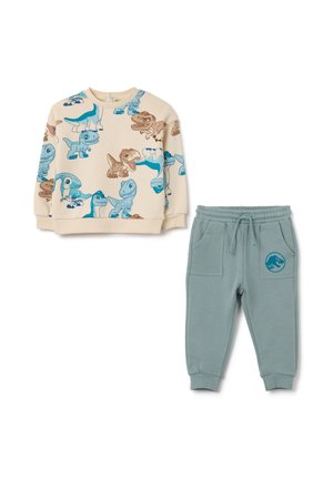 Tenue de sport pour enfants : sweat crème en polaire avec des motifs de dinosaures bleus et bruns ; pantalon de jogging teal avec poches latérales et logo de dinosaure.