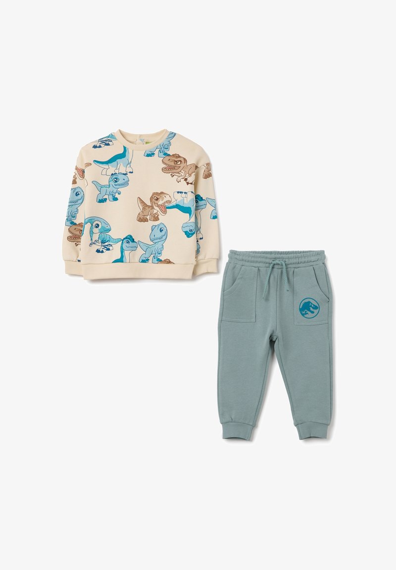 Kinderen sweatoutfit: crèmekleurige fleece pullover met blauwe en bruine dinosaurussenprints; teal jogger broek met zijzakken en dinosaurussenlogo.