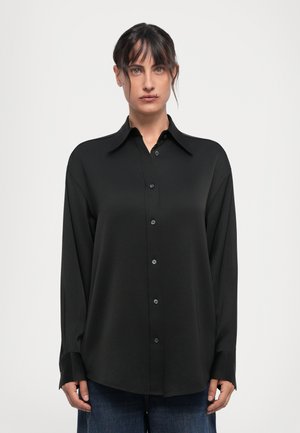Black button-up shirt with long sleeves, a pointed collar, and a smooth texture. Features matching buttons down the front and tapered cuffs.