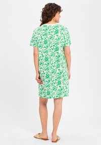 Korte mouw jurk met een groen bloemenpatroon op een witte achtergrond, met een ontspannen pasvorm die net boven de knieën valt.