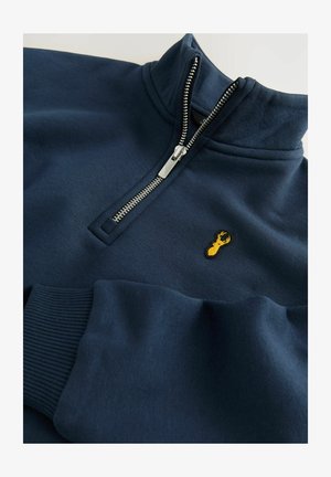 Jūras spēku zipsweatshirt ar augstu apkakli, ribu aprocēm un dzeltenu izšūtu omāru logotipu uz krūtīm. Mīksts, teksturēts audums.