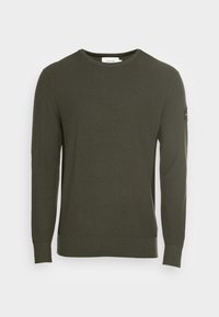 Maglione a maniche lunghe verde scuro con una superficie strutturata a costine, scollo tondo e una toppa con logo sulla manica sinistra.