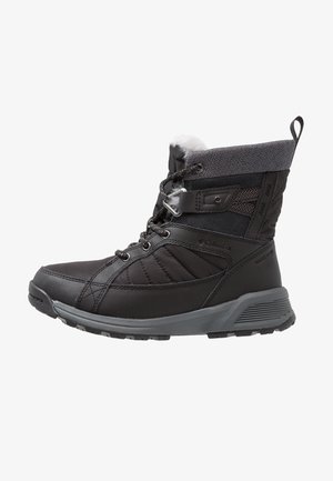 Bota de invierno acolchada negra con suela gris, cordones delanteros, puño de tela y forro de piel, diseñada para el frío y una buena tracción.