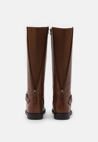 Brązowe skórzane kozaki do kolan z wysokim zamkiem z tyłu, o gładkiej fakturze, kwadratowym nosku i akcentem z klamrą z boku.
