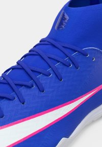 Μπλε αθλητικό παπούτσι με υφή από συνθετικό υλικό, λευκή και ροζ λωρίδα έμφασης, ενισχυμένο αστράγαλο και επίπεδα κορδόνια.