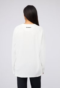 Weißes Langarmoberteil aus strukturiertem Strickstoff, mit gerippten Bündchen und einem schwarzen "Mammut"-Logo am hinteren Halsauschnitt. Glattes, leichtes Design.