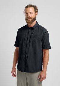 Korte mouwen zwart shirt van lichtgewicht stof met een knoopsluiting aan de voorkant en een borstzak, met een relaxte pasvorm en een gladde textuur.