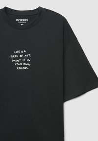 Czarny oversize'owy t-shirt wykonany z bawełny, z krótkimi rękawami i okrągłym dekoltem. Na białym nadruku znajduje się napis: "Życie to dzieło sztuki. Maluj je swoimi kolorami."