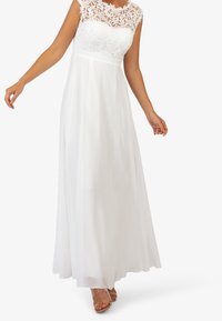 Bílé maxi šaty s krajkovým rukávkem, květinovým krajkovým živůtkem, splývavou látkou a hladkou texturou, zdůrazněné přiléhavým pasem.