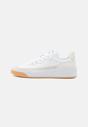 Biało-beżowy niski sneaker z gumową podeszwą, sznurowany z przodu i grubą białą podeszwą na platformie, widok z boku na jednolitym tle.