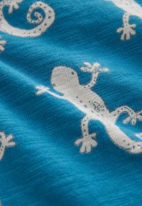 Blåt stof med hvide firbenmønstre, inklusive detaljerede teksturer og former af krybdyrene i forskellige positioner og designs.