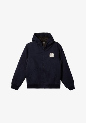 Chaqueta con capucha de color navy, con cremallera frontal, puños acanalados y dos bolsillos laterales. Presenta un logo circular en el lado izquierdo del pecho. Textura suave.