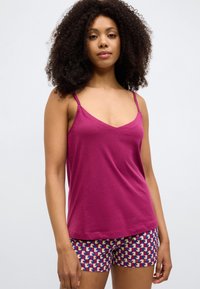 Top magenta sem mangas com alças finas e decote em V, combinado com calções estampados nas cores azul, rosa e creme.