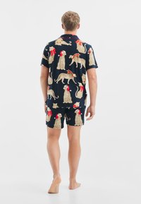 Granatowy zestaw piżamowy z nadrukiem w lamparcze cętki i świątecznymi akcentami, w tym czapkami i szalikami; krótki rękaw i krótki krój spodenek.