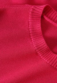 Maglione lavorato a maglia di un vivace colore rosa con una finitura testurizzata. Presenta un colletto a girocollo a coste e maniche lisce, che mostrano una cucitura uniforme.