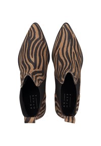 Zapatos de punta afilada con un patrón de estampado de cebra en marrón y negro. Material de tela suave con un detalle elástico en el lateral y una lengüeta para tirar en la parte trasera.