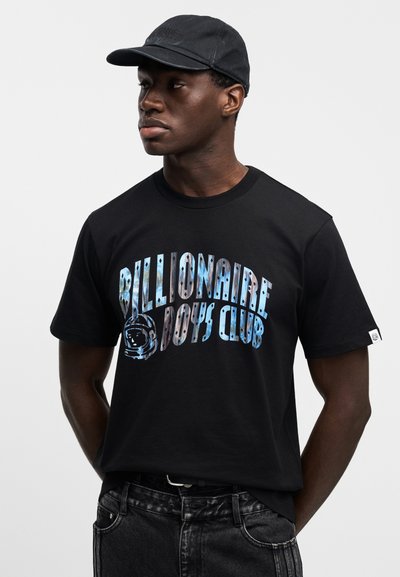 Μαύρο βαμβακερό μπλουζάκι με πολύχρωμ ο γραφικό σχέδιο, «Billionaire Boys Club» και στρογγυλή λαιμόκοψη. Συνδυασμένο με σκούρες τζιν παντελόνες.