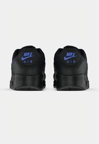 Zwarte sportieve sneakers met blauwe Nike-logo's. Voorzien van een gestructureerde achterkant, een gevoerde kraag en een rubberen zool voor grip.