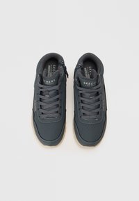 Para ciemnoszarych wodoodpornych sneakersów Skechers z sznurówkami i bocznymi zamkami, widziana z góry na jasnym tle.