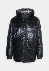 Veste d'hiver noire brillante matelassée avec capuche, poches avant et logo "Tommy Jeans" sur la poitrine, dotée de poignets élastiques et d'une fermeture éclair.