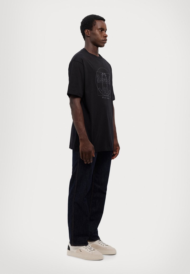 Črna bombažna majica s kratkimi rokavi ima na sprednji strani grafični dizajn in sproščen kroj. Ujemita jo temno modra kavbojka in svetli športni čevlji.