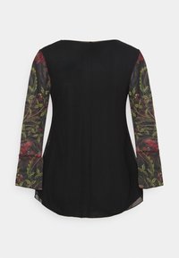 Top nero con maniche trasparenti a motivo floreale che presentano disegni botanici rossi e verdi, orlo arrotondato e chiusura con zip posteriore.