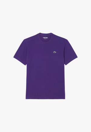 Camiseta de algodón morada con mangas cortas, escote redondo y un pequeño logo de cocodrilo verde en el lado izquierdo del pecho. Textura suave.