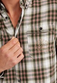 Geruite shirt in groene, witte en roze tinten; gemaakt van katoen; heeft een borstzak met geborduurde details en zwarte knopen.