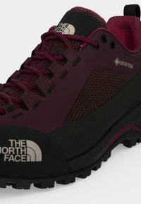 Κοντινή λήψη μποτάκι πεζοπορίας The North Face μπορντό και μαύρο με ύφασμα Gore-Tex και ανθεκτική σόλα για υπαίθρια χρήση.