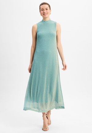 Helles Teal, ärmelloses Maxikleid mit hohem Hals. Strukturiertes Gewebe funkelt dezent, fließende Silhouette und weicher Saum. Trägt dazu nudefarbene Absätze.