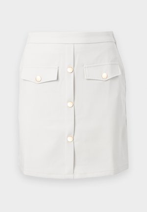 Balta medvilninė sijonas su priekiniais sagomis ir dviem kišenėmis krūtinėje. Savo dizainu atkreipia dėmesį auksinio tono sagomis ir aptaku struktūrizuota išvaizda.