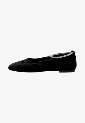 Ballerine in velluto nero con punta affusolata e un bordo decorativo di strass lungo il tallone. Texture morbida e suola a profilo basso.
