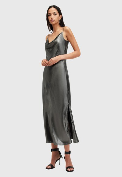 Robe sans manches à col drapé en satin gris anthracite. Présente une fente latérale et une texture lisse, associée à des escarpins à bride de cheville noirs.