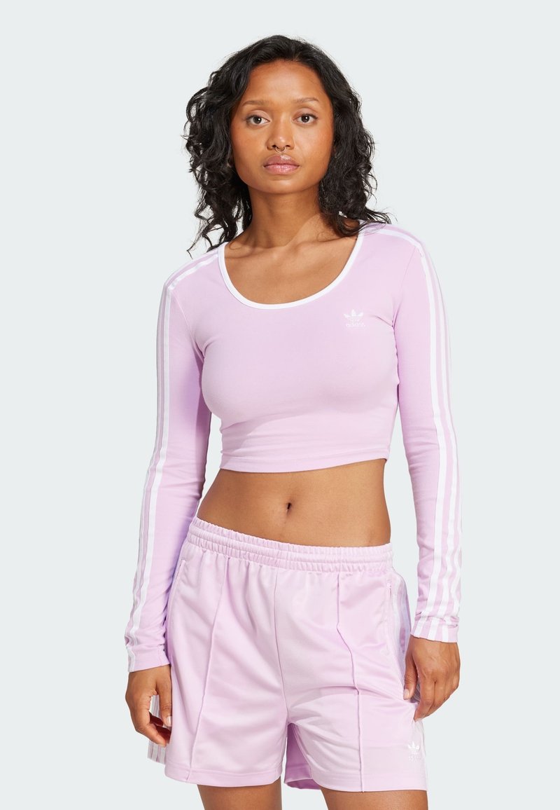 Ljuslila långärmad crop top med vita ränder längs ärmarna, matchad med ljuslila shorts som har resårmidja.