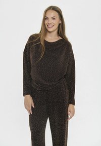 Set da lounge marrone glitterato composto da una blusa morbida e drappeggiata con maniche lunghe e pantaloni con vita elasticizzata. Texture morbida con dettagli scintillanti.