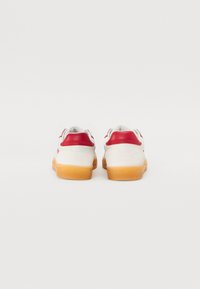 Hvite sneakers med røde detaljer og beige såler. Rund form med et glatt læroverdel og polstret krage for komfort.