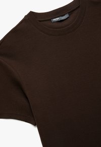Brun ribbet t-shirt med rund halsudskæring og korte ærmer. Lavet af blødt stof, har den en glat tekstur og et enkelt design.