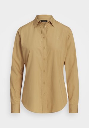 Chemise beige à manches longues avec col, manches retroussées et logo subtil sur le côté gauche de la poitrine.