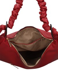 Sac à main rouge en cuir texturé, avec une fermeture éclair, des poignées plissées et une doublure beige avec logo imprimé.