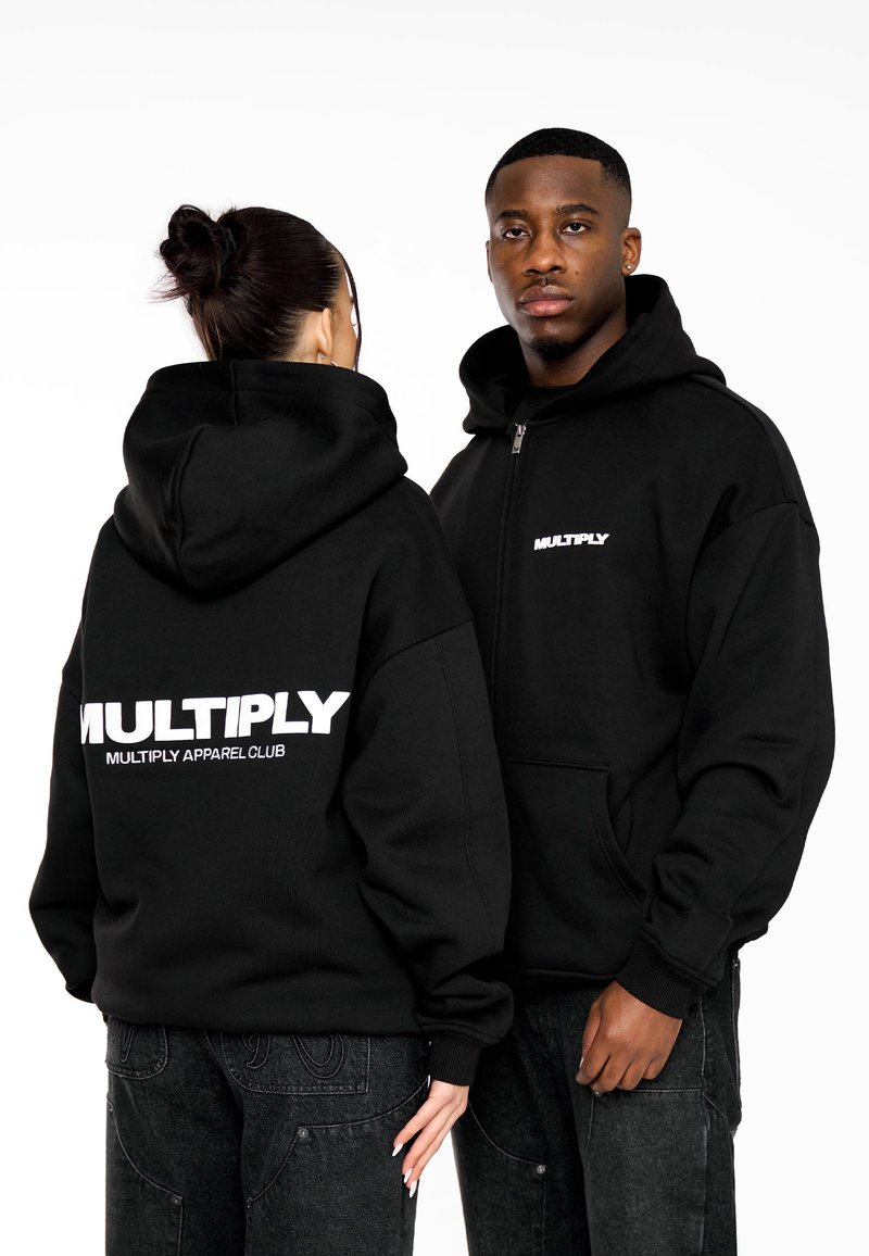Černé zipové mikiny s kapucí vyrobené z měkké tkaniny, s velkým bílým logem "MULTIPLY" na zadní a přední straně, s běžným střihem a klokaními kapsami.