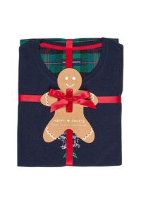 Navy katoenen pyjama-set met geruite shorts, verpakt met een rode strik. Een tag in de vorm van een peperkoekmannetje heeft de tekst "Gelukkige Shorts" en feestelijke graphics.