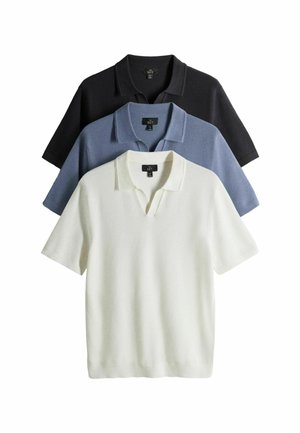 Drie polo's met korte mouwen opgestapeld, kleuren zwart, blauw en wit, met open kragen en zachte, getextureerde stof.