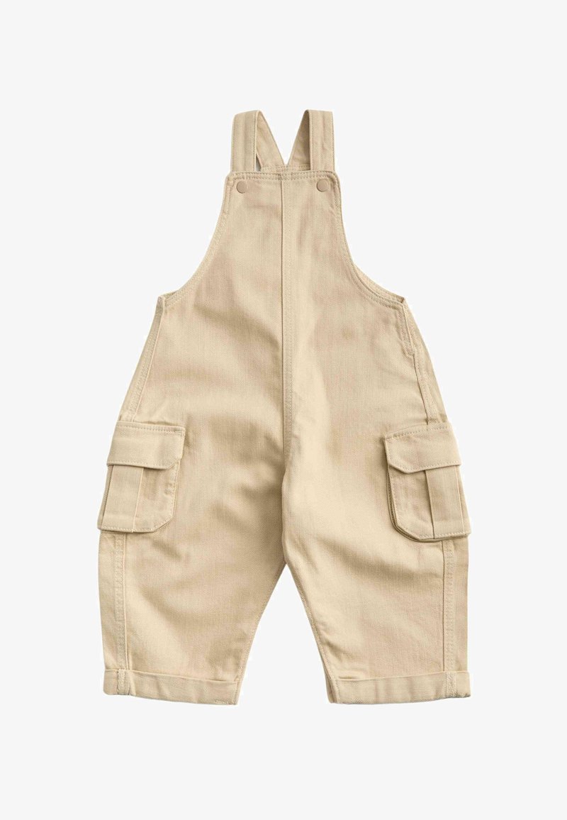 Peto beige para niño pequeño con tirantes ajustables en los hombros, botones delanteros, bolsillos laterales tipo cargo y pantalones remangados.