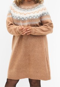 Robe-pull en maille beige avec un empiècement texturé et à motifs en gris, blanc et rouille, comprenant des manches longues et un col rond.