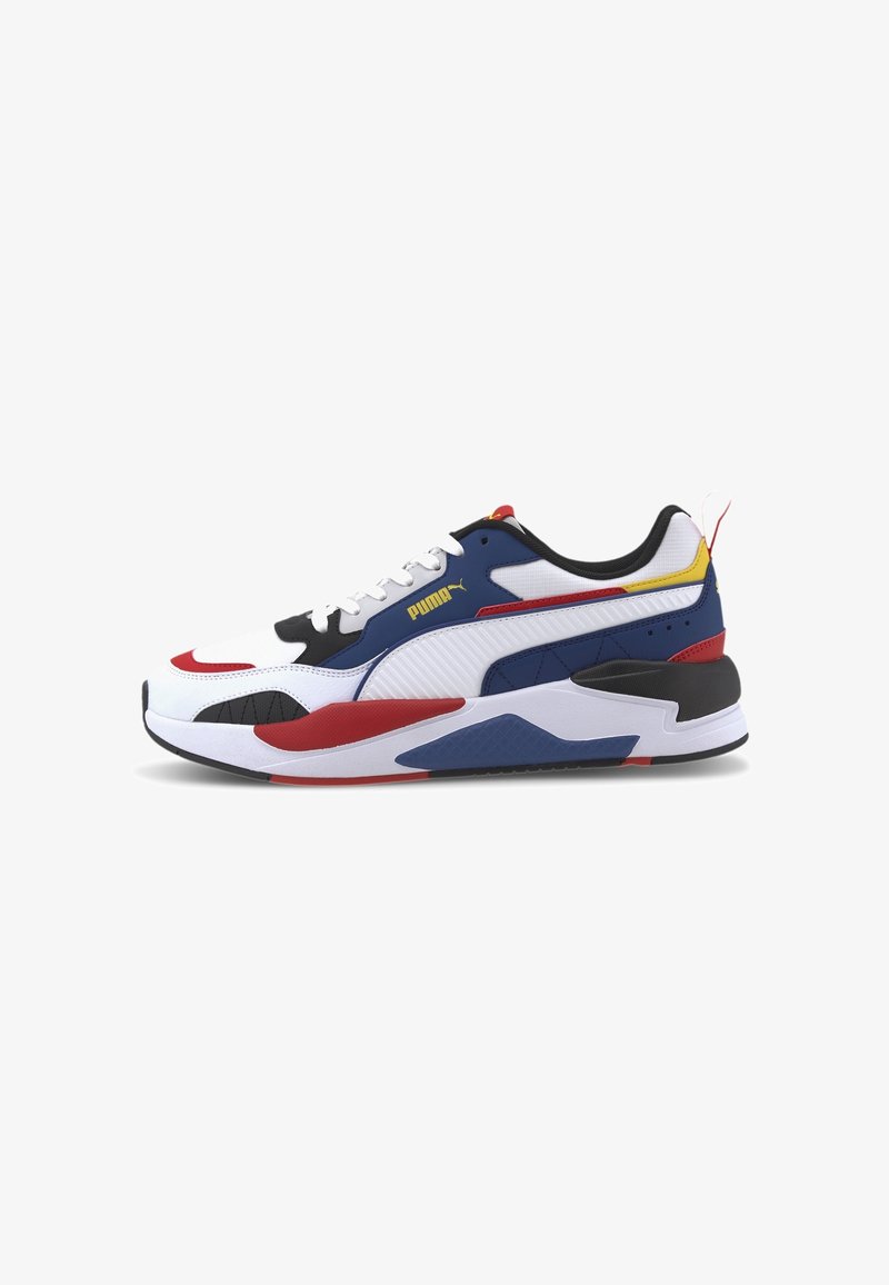 Baskets Puma blanches, bleues, rouges, jaunes et noires avec un design à lacets, une semelle épaisse et coussinée, un logo latéral et une languette arrière.