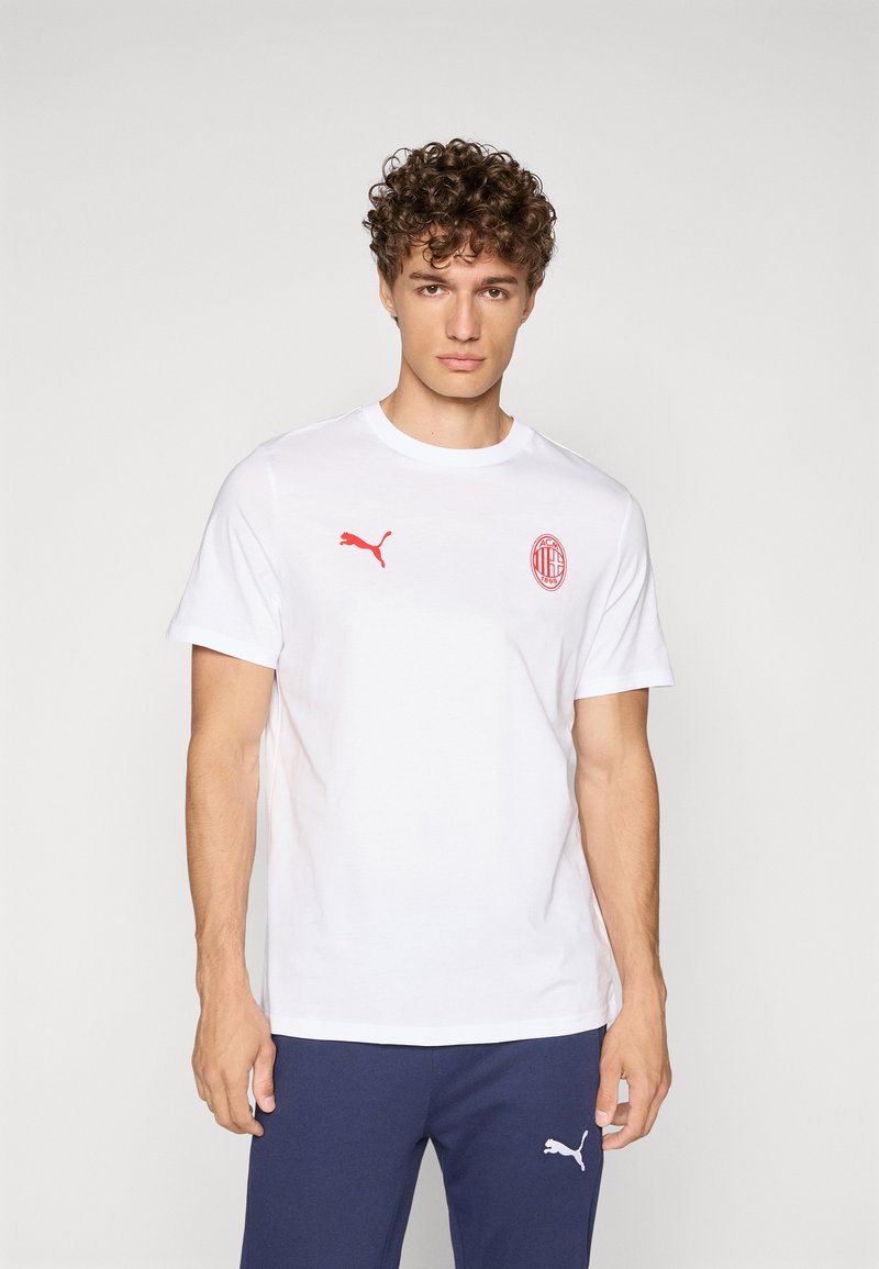 Hvid bomulds-T-shirt med et rødt Puma-logo på venstre bryst og et rødt AC Milan-emblem på højre bryst. Korte ærmer, rund halsudskæring.