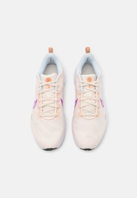 Scarpe sportive leggere con tomaia in rete color crema, dettagli viola e colletto imbottito blu, dotate di linguetta arancione e lacci.